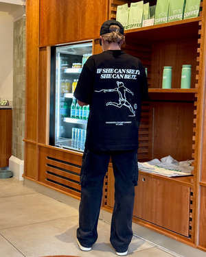 Kyah Simon wearing the back of the black SHE CAN Tee by KS Label