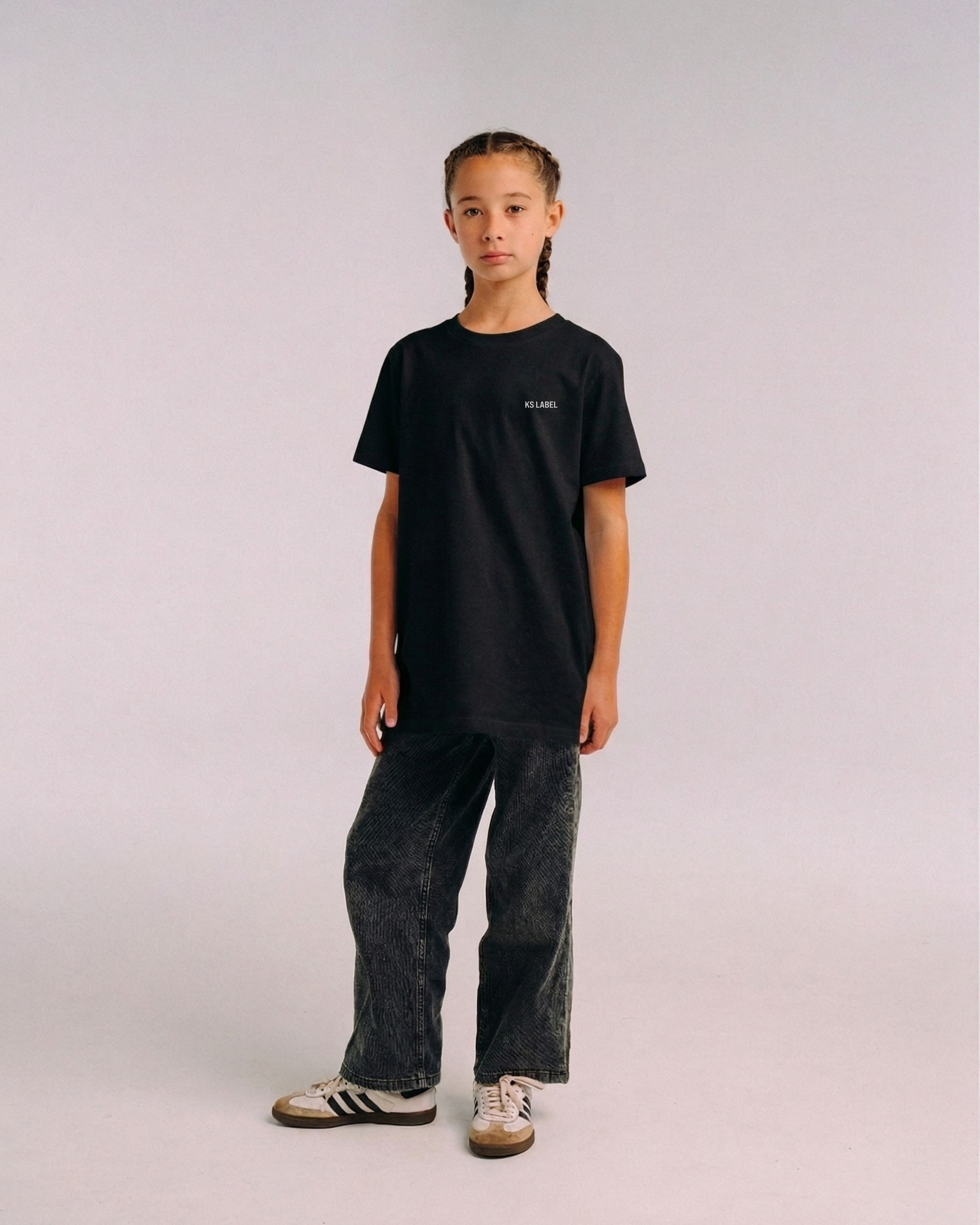 Model wearing the front of the black SHE CAN Youth tee by KS Label