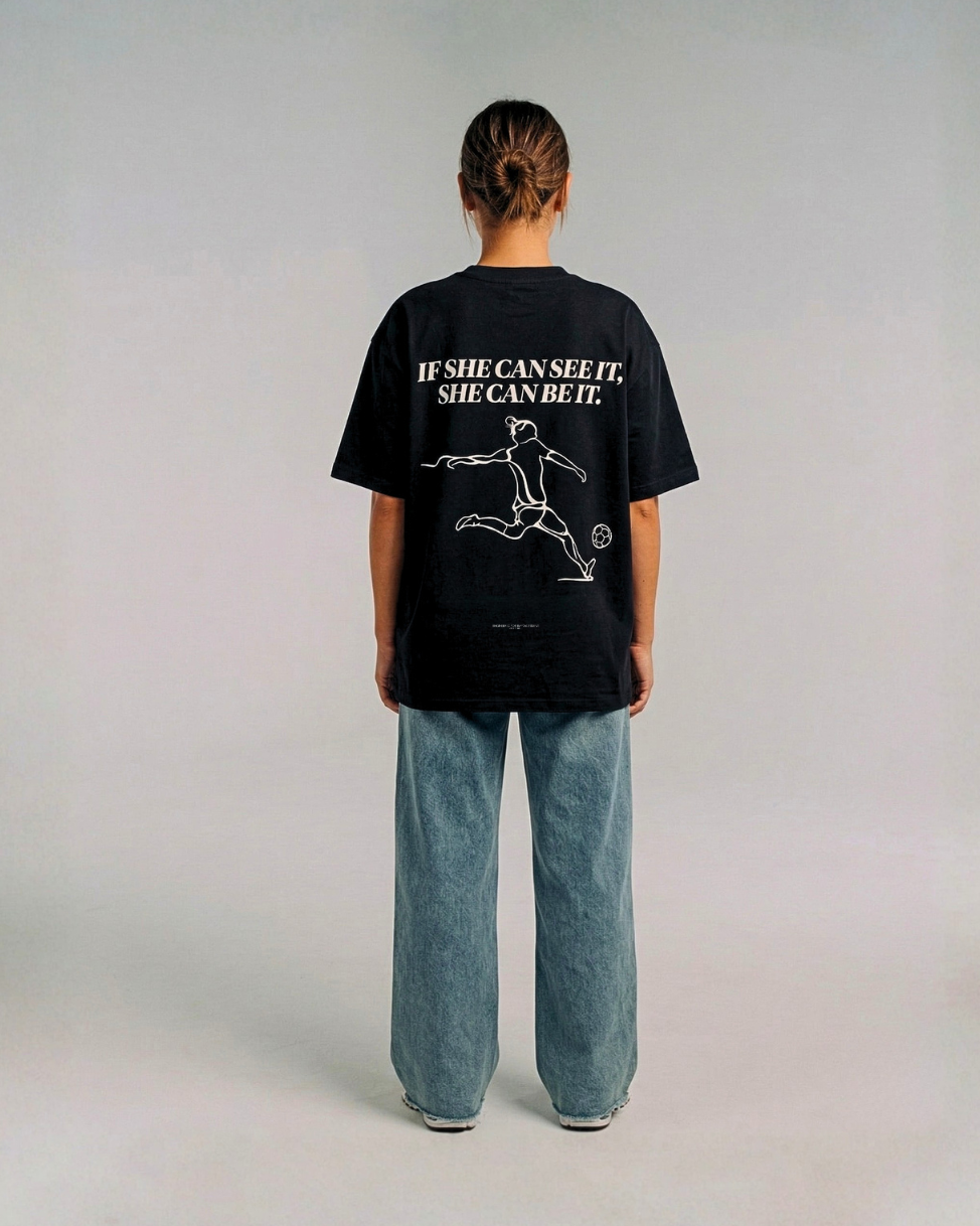 Model wearing the back of the black SHE CAN Tee by KS Label