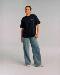 Model wearing the front of the black SHE CAN Tee by KS Label