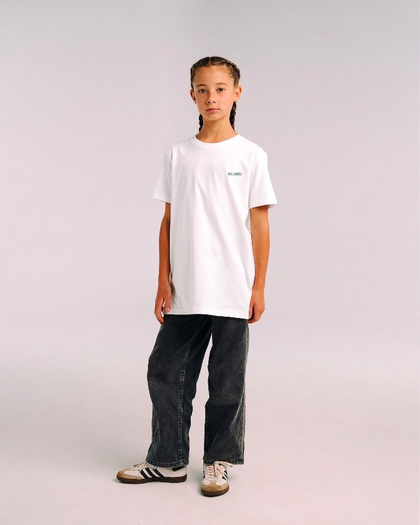 Model wearing the front of the white SHE CAN Youth tee by KS Label