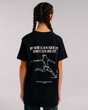 Close view of a model wearing the back of the black SHE CAN Youth tee by KS Label