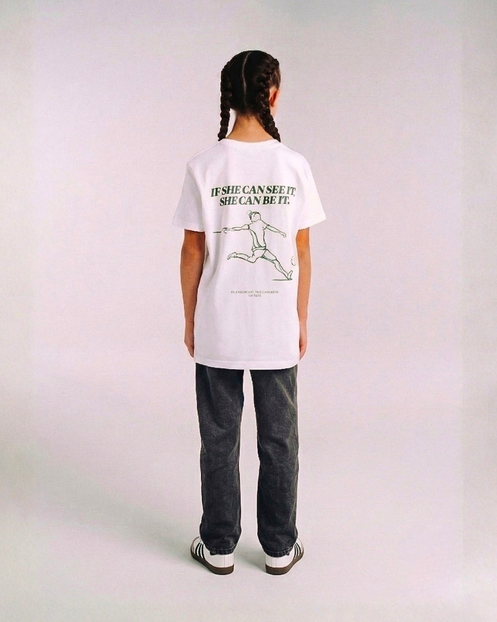 Model wearing the back of the white SHE CAN Youth tee by KS Label